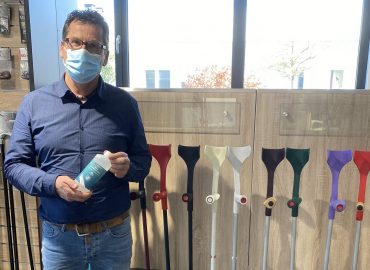 Geschäftsführer Carsten Diekmann mit Mundschutz und Desinfektionsmittel posiert vor Gehhilfen.